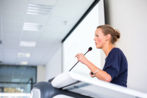 Pretty, young business woman giving a presentation in a conference/meeting setting (shallow DOF; color toned image)