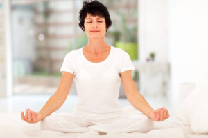 beautiful middle aged woman meditation on bed at home